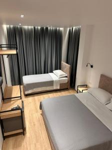 a bedroom with two beds and a window with curtains at Logan Rooms Berat in Berat