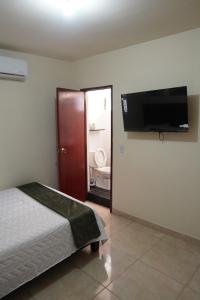 a bedroom with a bed and a flat screen tv at Casa Esperanza in Cali