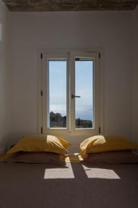 two beds in a room with two windows at Villa Petra in Andros