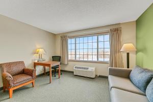 a hotel room with a couch and a desk and a window at Country Inn Walker in Walker