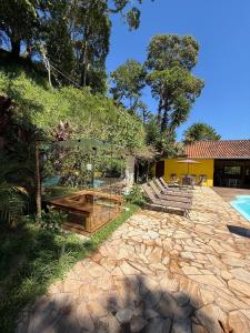 a house with a stone patio and a yellow building at Cabana Refúgio da Mata in Juquitiba