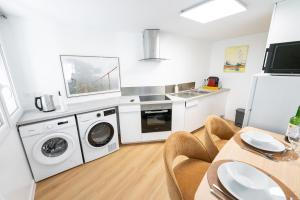a kitchen with white appliances and a table with chairs at Appartement rénové avec parking quartier historique in Bordeaux