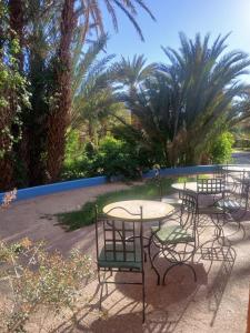 a group of tables with chairs and palm trees at Chez Moulay Ismail in Agdz