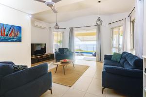 a living room with blue couches and a tv at Bahari Villa Beachfront in Port Louis