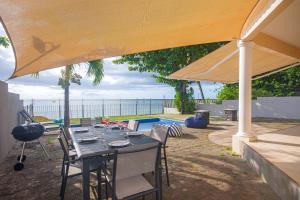 a table and chairs under a large umbrella at Bahari Villa Beachfront in Port Louis