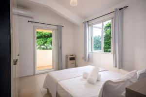 a white bedroom with a bed and two windows at Bahari Villa Beachfront in Port Louis +15 photos