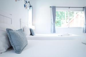 a white bedroom with a window and a pillow at Phi Phi Indigo Hotel in Phi Phi Islands