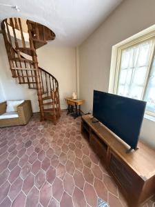 a living room with a flat screen tv and a staircase at PALIO LIMANI APARTMENTS in Spetses