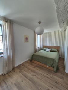 a bedroom with a green bed and a window at La place in Pont-de-Vaux