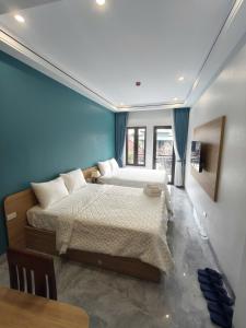 two beds in a room with blue walls and a table at Tam Coc Sunflower Hotel in Ninh Binh