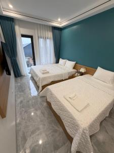 a bedroom with two beds and a blue wall at Tam Coc Sunflower Hotel in Ninh Binh