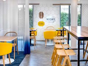a dining room with yellow chairs and tables at Hôtel ibis Styles Vichy Centre in Vichy