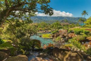 a river in a garden with trees and rocks at NEW Sunset Hideaway with Beach Access Pools & AC in Princeville +67 photos