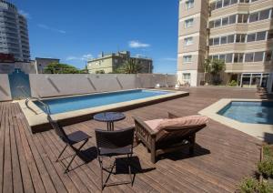 a deck with chairs and a table next to a pool at hotel Villa Gesell Spa in Villa Gesell
