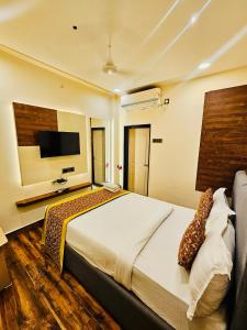 a bedroom with a large bed and a flat screen tv at Shankar Bhavan By Vinayak Hotels in Brahmapur