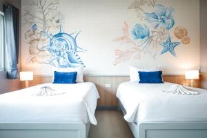 two beds in a room with a mural on the wall at Phi Phi Indigo Hotel in Phi Phi Islands
