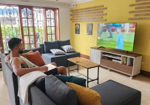 a man sitting on a couch watching a television at Paisa Hostel Medellín in Medellín