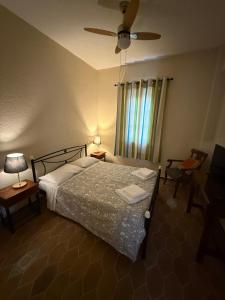 a bedroom with a bed and two chairs and a ceiling fan at PALIO LIMANI HOUSE in Spetses