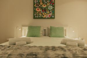 a bed with green pillows and a painting on the wall at Termas do Gerês Studio in Geres +59 photos