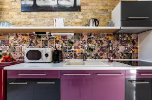 a kitchen with purple cabinets and a tile wall at Mignon Szeged Apartman in Szeged