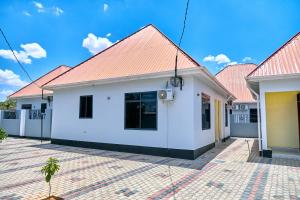 a white house with a red roof at Ngao Apartment and Suites Dodoma in Dodoma