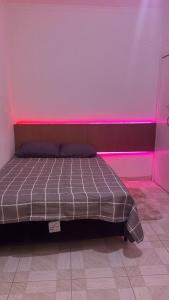 a bed in a room with a pink light at Host Família Catarina in Guarulhos