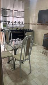 a glass table and two chairs in a kitchen at Host Família Catarina in Guarulhos