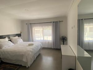 a bedroom with a white bed and a window at The 'C' Apartments in Mansa +6 photos