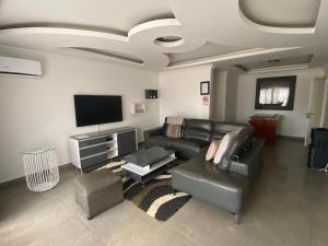 a living room with a leather couch and a flat screen tv at The 'C' Apartments in Mansa