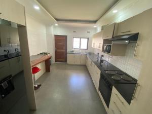 a large kitchen with white cabinets and black appliances at The 'C' Apartments in Mansa