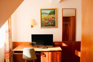 a room with a desk with a computer and a painting of flowers at Hotel Restaurant Blumenhof in Baesweiler