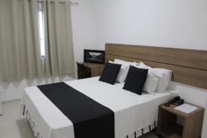 a bedroom with a large bed with black and white pillows at Hotel Irmãos Vaz Br 116 - Entronc. De Jaguaquara in Jaguaquara