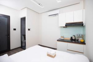 a room with a bed and a kitchen with white cabinets at Board & Beyond House in Danang