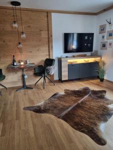 a living room with a wooden floor with a table and a tv at Ferienwohnung Ehring in Kiefersfelden