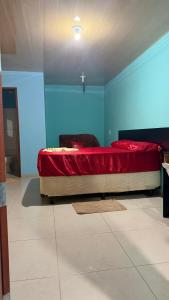 a bedroom with a bed with red sheets and blue walls at Hotel e Residencial Solar in Uruara