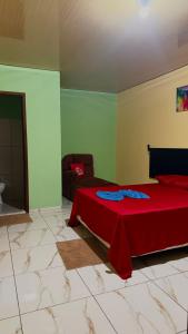 a bedroom with a red bed and a couch at Hotel e Residencial Solar in Uruara