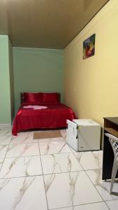 a bedroom with a bed with red sheets and a table at Hotel e Residencial Solar in Uruara +4 photos