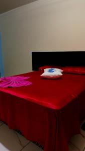 a red bed with red sheets and a white pillow at Hotel e Residencial Solar in Uruara