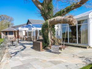 a tree on a patio with a swing at Willow Apartment - Gower in Swansea