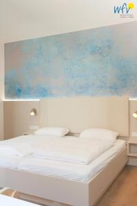 a bedroom with a white bed with a painting above it at Stine's Hus Ferienwohnung 2 in Borkum