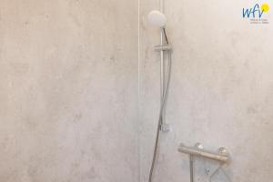 a shower with a shower head on a wall at Stine's Hus Ferienwohnung 2 in Borkum +14 photos
