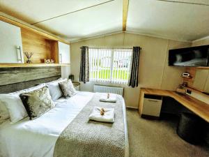 a bedroom with a large bed with two towels on it at Static in Peak District Ashbourne Heights Derbyshire Play Park Indoor Pool in Tissington