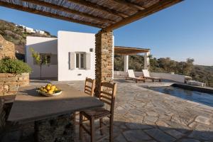 a patio with a table and chairs next to a pool at Villa AVRA, a serene Cycladic villa with private pool overlooking the Aegean Sea in Batsi