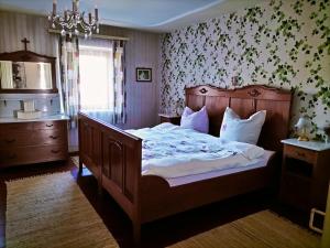a bedroom with a large wooden bed with a chandelier at B&B Herberg im Eichberg in Dettighofen