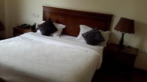 a bedroom with a white bed with black pillows at FT Hotel in Addis Ababa