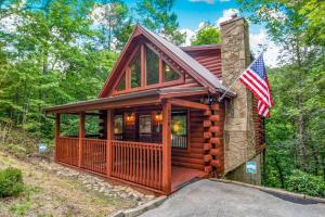 a log cabin with an american flag in front of it at Freedom Creek Hideaway-Veteran Host-Pet Friendly-Single nights-Newly Renovated!! in Pigeon Forge