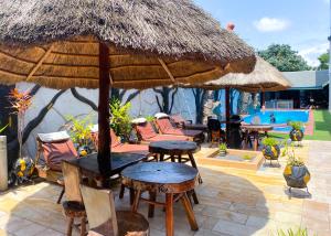 a patio with tables and chairs and an umbrella at MJ Grand Hotel in East Legon