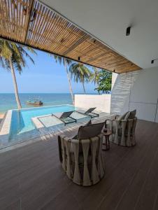 a patio with chairs and a table and a pool at Pano Samui Beachfront Villas in Nathon Bay