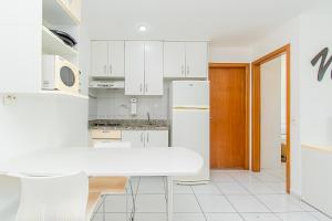 a kitchen with white cabinets and a white table at Premier Residence Residencial em Brasília 67961 in Brasília