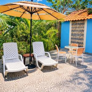 a group of chairs and a table with an umbrella at Spacious Home with Private Pool in San Felipe de Puerto Plata